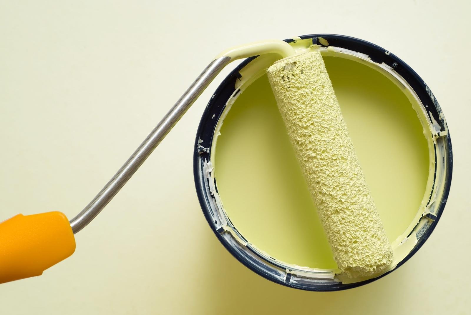 "Close-up of a professional painter applying a fresh coat of paint on a wall with a paint roller."